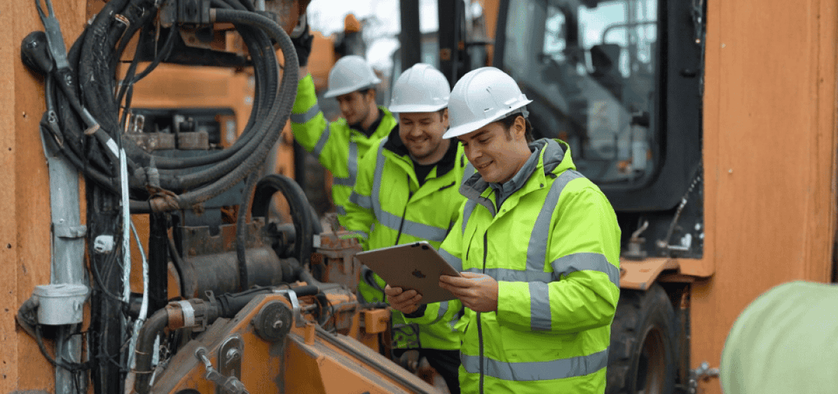 Construction technicians using a tablet to troubleshoot heavy machinery on-site