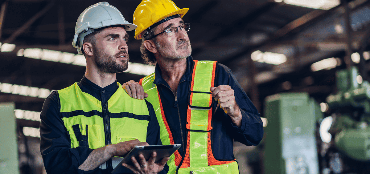 Industrial technicians reviewing equipment data on a tablet inside a manufacturing facility